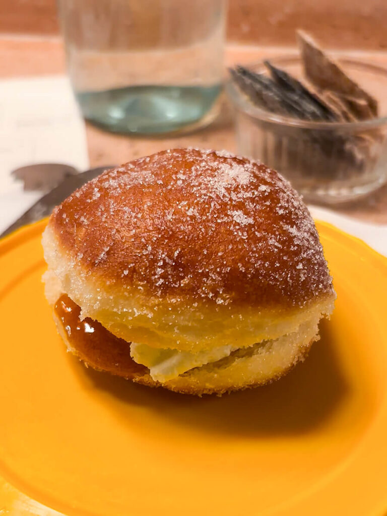 A sugar-powdered donut stuffed with rosemary goat cheese and honey. It's on a plate, and it's from Pick & Cheese in the Seven Dials Market in London