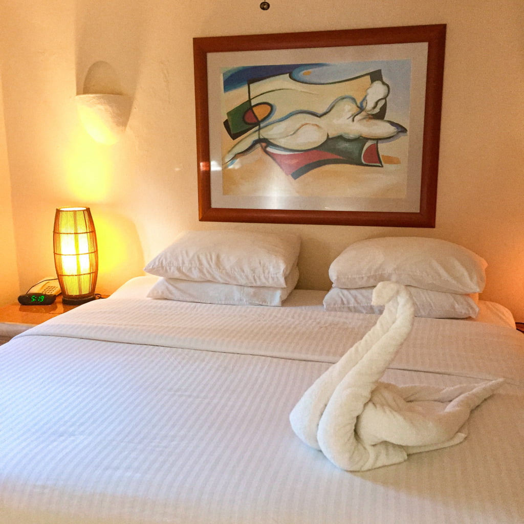 Honeymoon suite in Aventura Mexicana Hotel in Playa del Carmen, Mexico, featuring a California King sized bed, towel art shaped as a swan, and a painting of a nude woman (Picasso style) over the bed.