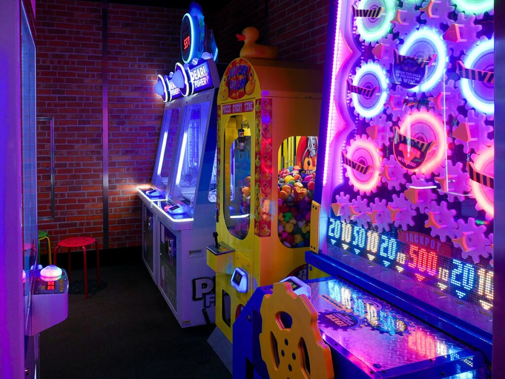 Arcade in the Carnival Radiance cruise ship, with low light but has bright neon signs