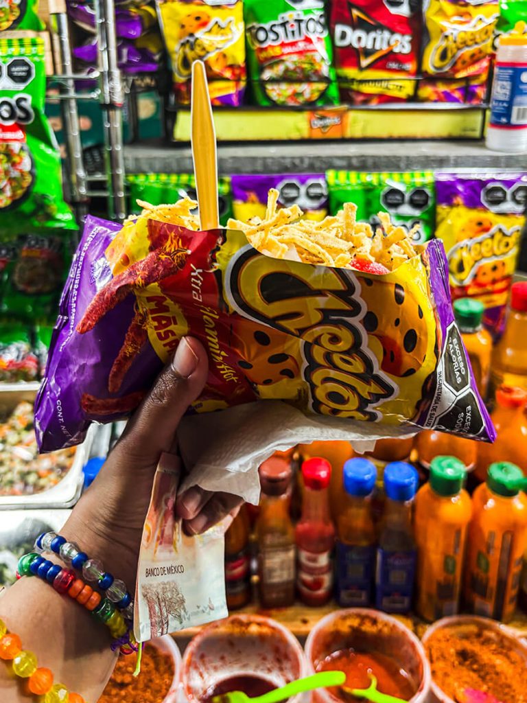 Cheetoloco, a bag of Mexican Hot Cheetos with tortilla chips, hot sauce, queso, and gummy rings. This is a street food dish sold at the vendors in Puerto Vallarta, Mexico, on the Malecon