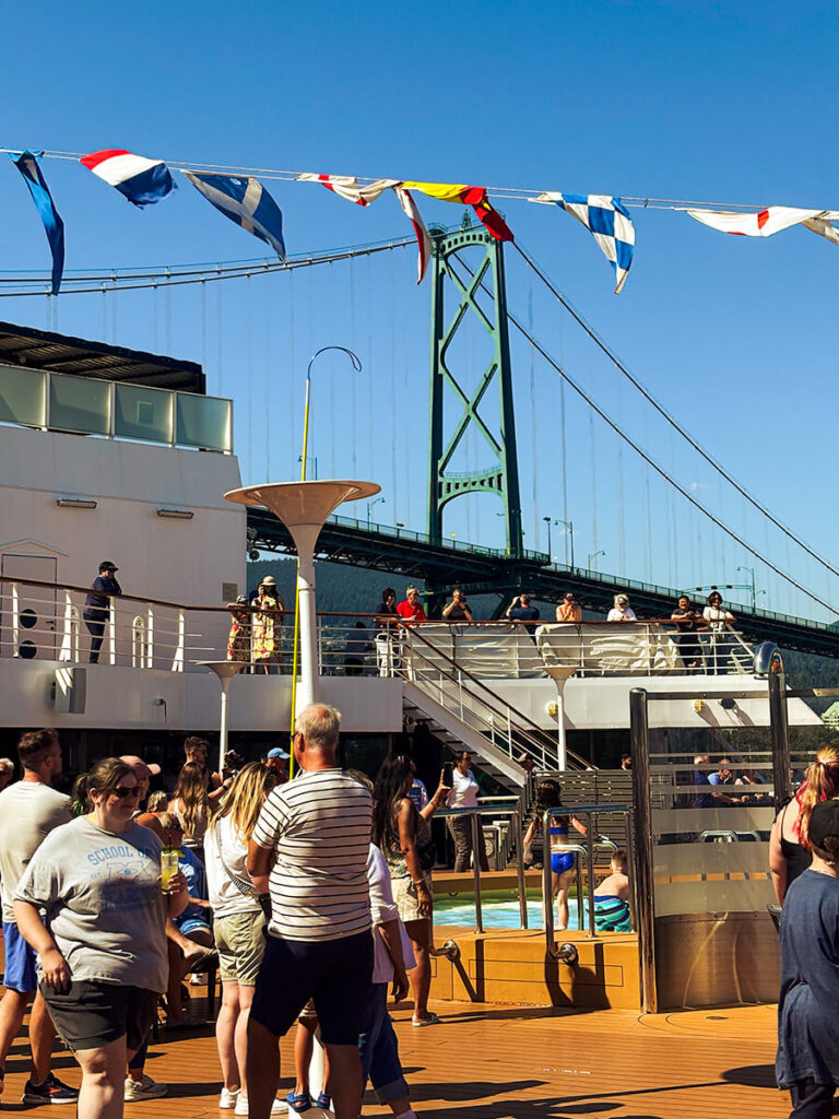 Passengers on the Sea view deck of Holland America Zaandam sailing under the Lions Gate Bridge, cruising to Alaska from Vancouver