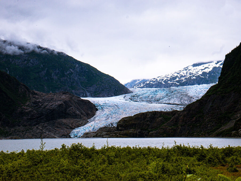 Mendenhall Glacier in Juneau, Alaska on a cloudy day with grass on the foreground