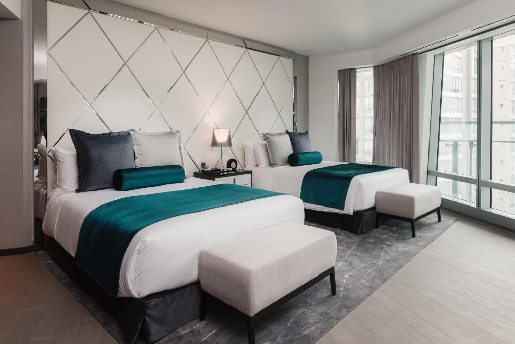 2 Queen sized beds in Paradox Vancouver with ceiling-to-floor windows overlooking Downtown Vancouver