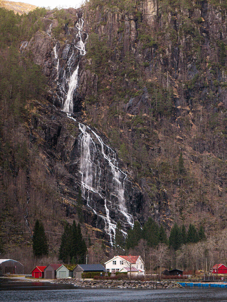 Kvernhusfossen, a large waterfull over a village of houses on the Mostraumen Strait in Norway