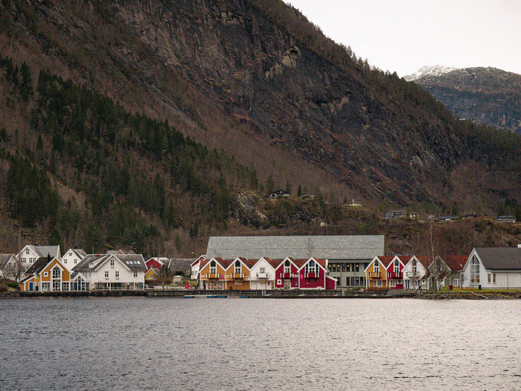 The village of Mo, a part of Modalen Municipality in Norway, on the Mostraumen Straight. Behind the village of colorful houses is a large mountain range