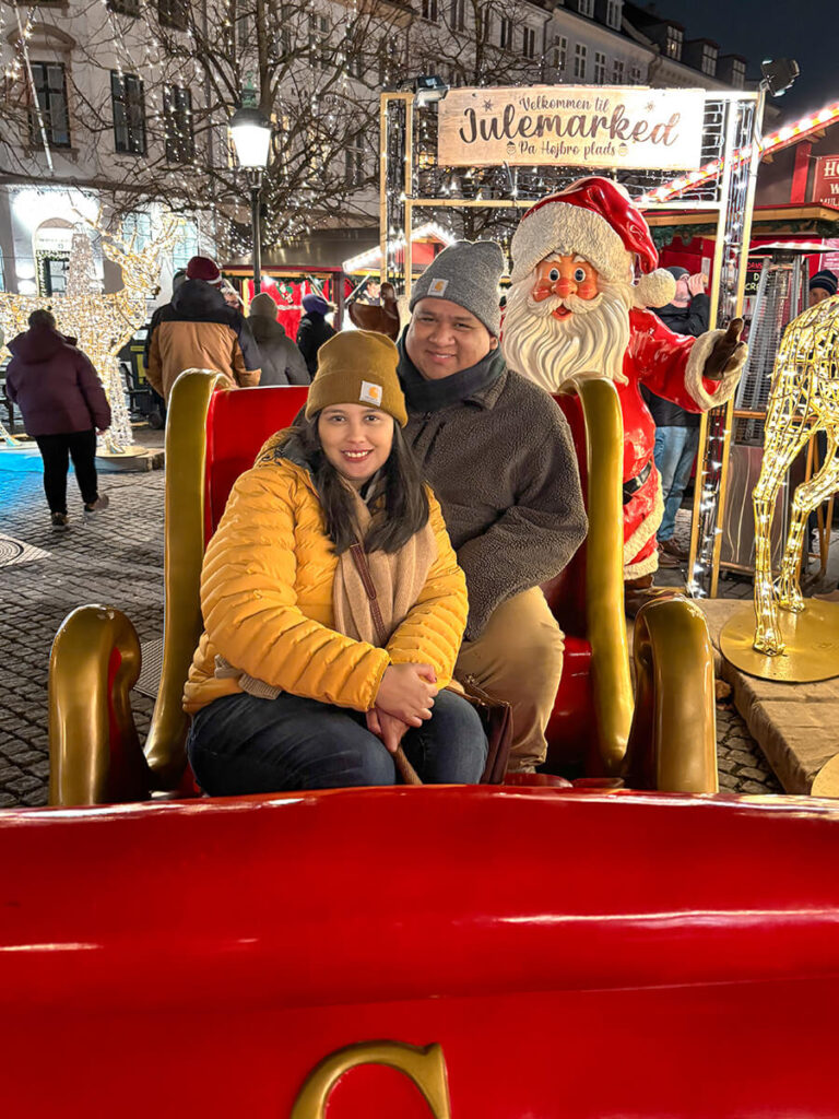 Hannah and Cecilio sitting on the red Santa sleigh at the Højbro Plads in Copenhagen