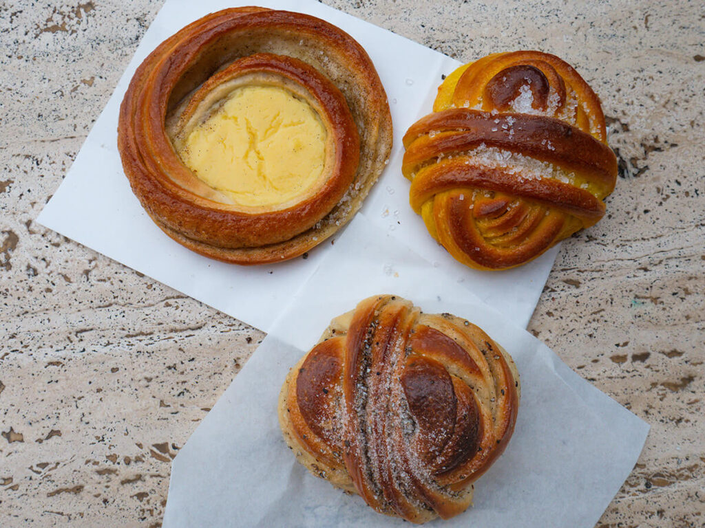 The vanilla cream bun, saffron bun, and cardamom bun on a table from Juno the Bakery in Copenhagen