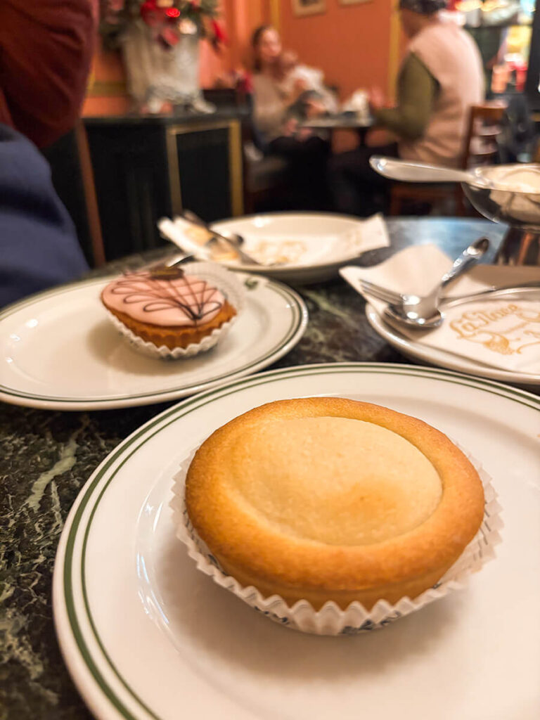A table of pastries from Conditori La Glace in Copenhagen. On the front is the linse, a tart made of shortbread with vanilla cream filling. Behind it is the mazarin, a pastry made of crust, marzipan, and icing