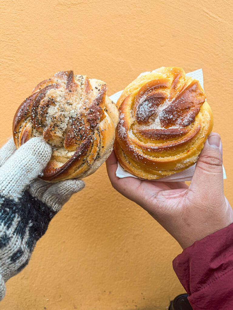 Hannah and Cecilio holding a cardamom and saffrom bun from Skt. Peders Bageri in Copenhagen